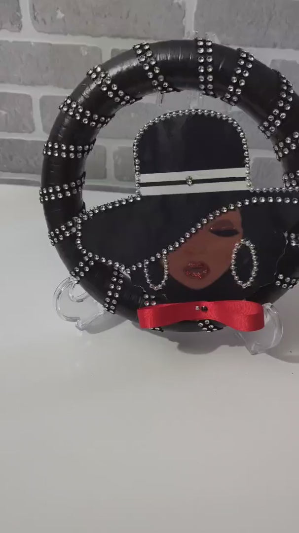 Decorative Lady Black Wreath with a stylized face design on a stand, featuring black hair, red ribbon, and silver embellishments.