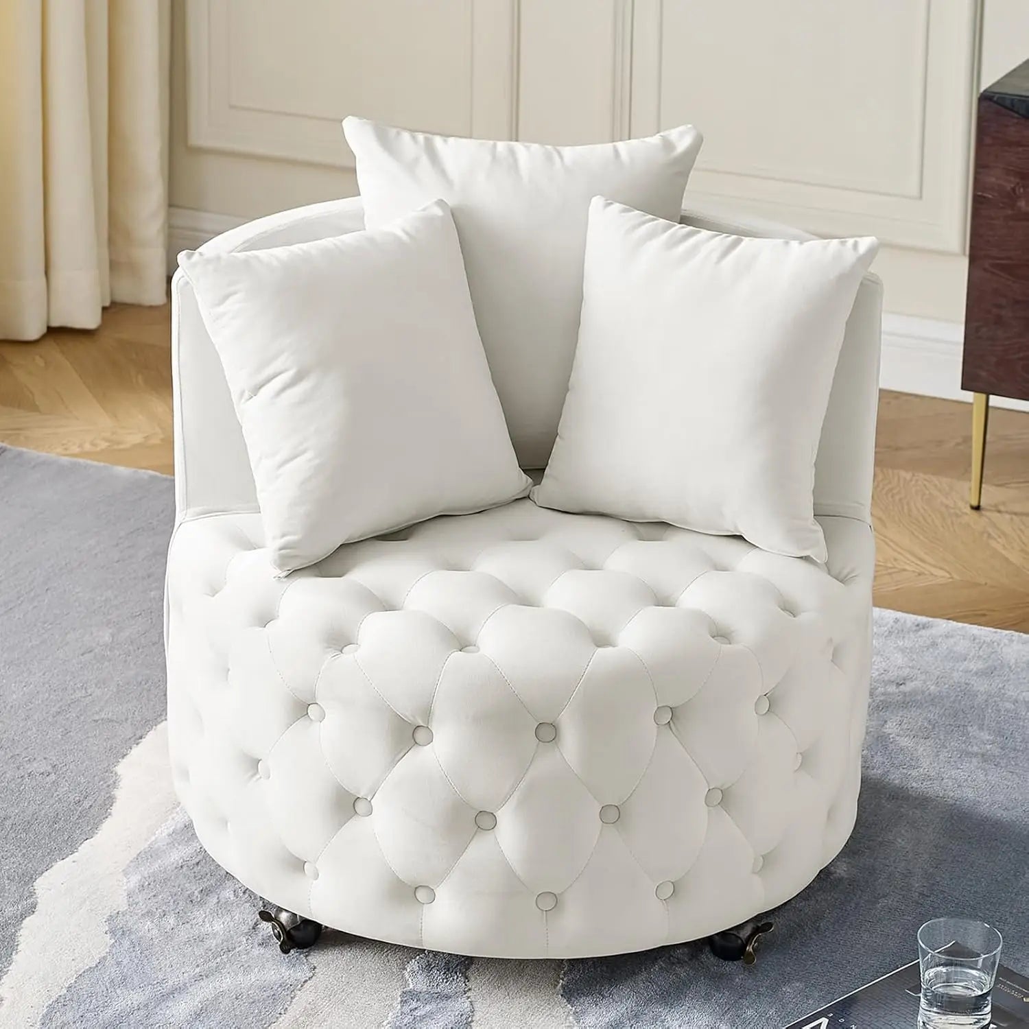 White tufted armchair with three pillows in a room setting